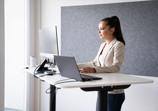 Woman standing on a standing desk with a laptop.
