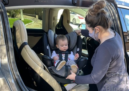 A baby being put in a rotating car seat.