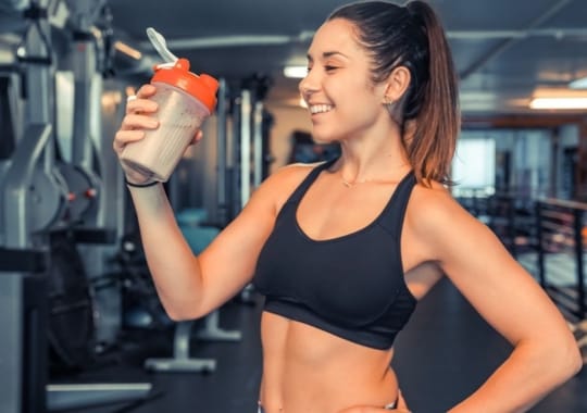 A lady holding a bottle of protein powder shake.