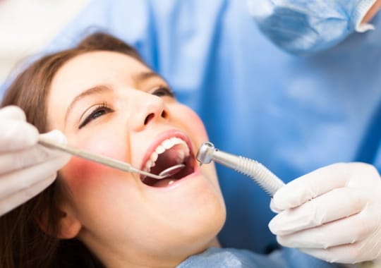 A dentist doing a tooth extraction on a woman.