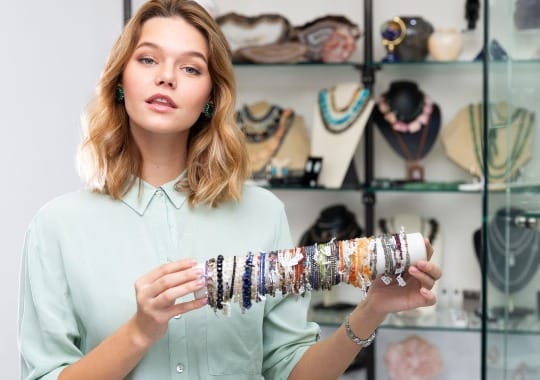 A lady holding different types of bracelets.