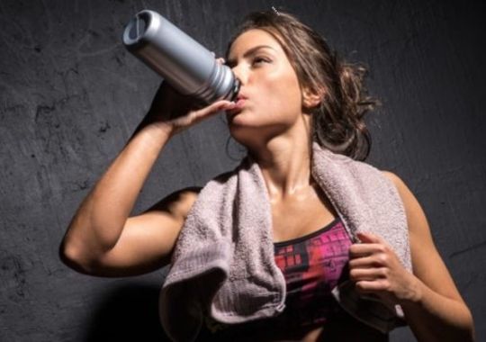 Woman drinking pre-working supplements.
