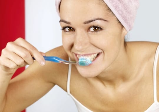A lady brushing her teeth.