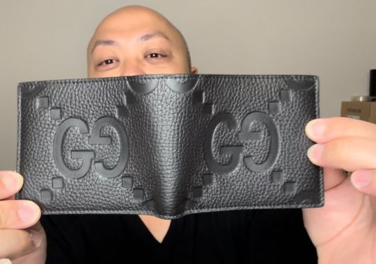 A man showing a Gucci wallet.
