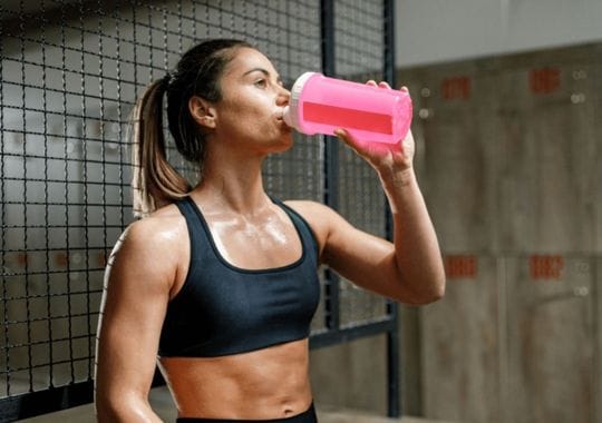 A woman drinking pre workout supplements.