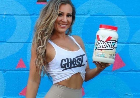 A woman with a bottle of Ghost protein powder.