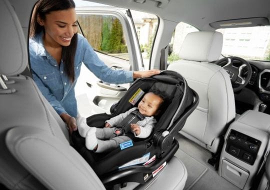 A woman putting her baby in a rotating car seat.