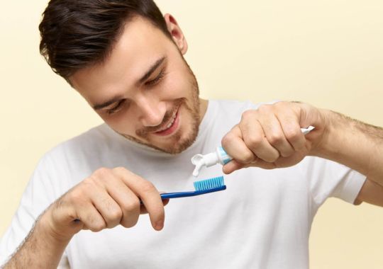 A man putting toothpaste on tooth brush.