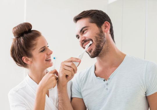 A Couple brushing their teeth.