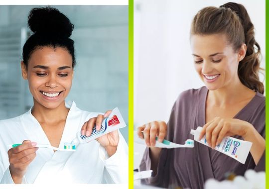 Two women putting toothpaste on their tooth brushes.