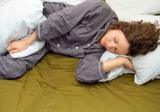A woman sleeping wearing pajamas.