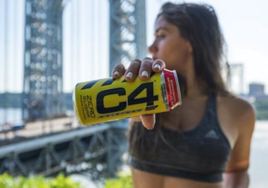 A woman holding a c4 canned energy drink.