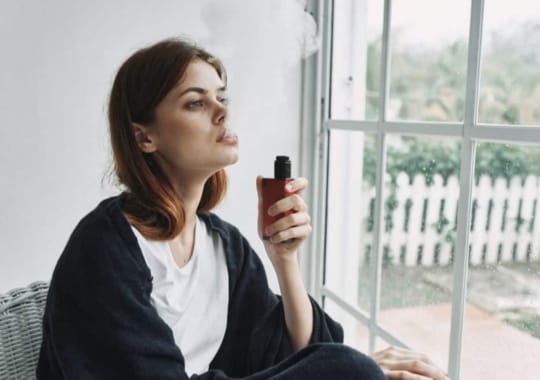 A woman holding a vape juice smoking. 