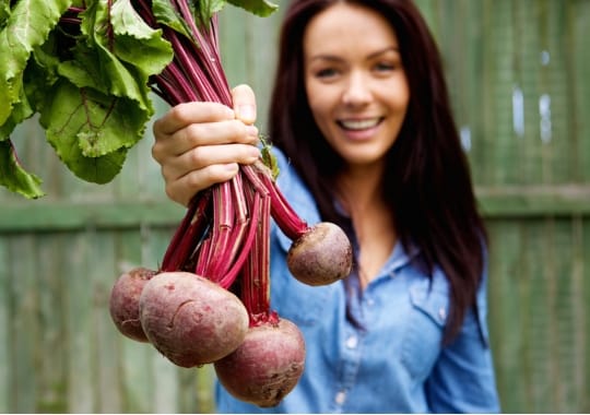 A lady holding beet root fruits.