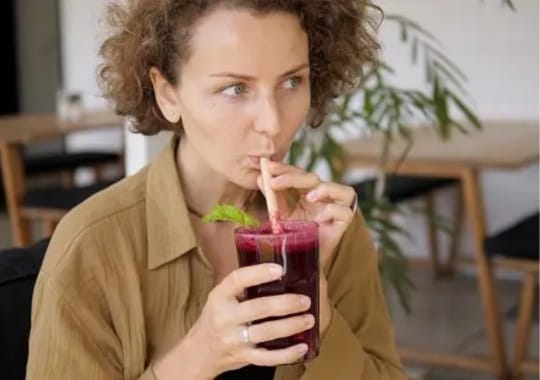 A woman drinking powdered beetroot juice.