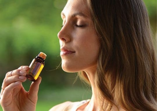 A lady smelling a bottle of essential oil.