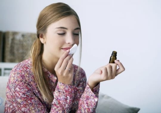A woman smelling a bottle of vanilla oil.