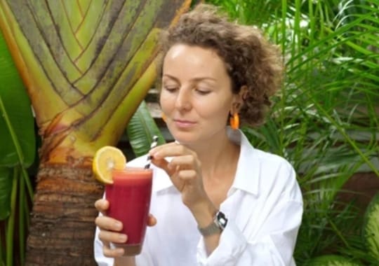 A woman holding a glass of beet juice.