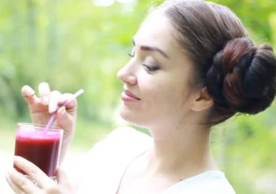 A lady holding a glass of superbeet juice.