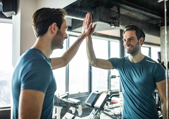 A happy man giving himself a high-five in a gym.