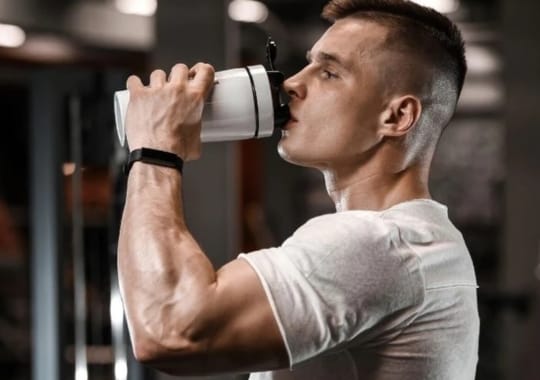 A man drinking pre-workout supplements.
