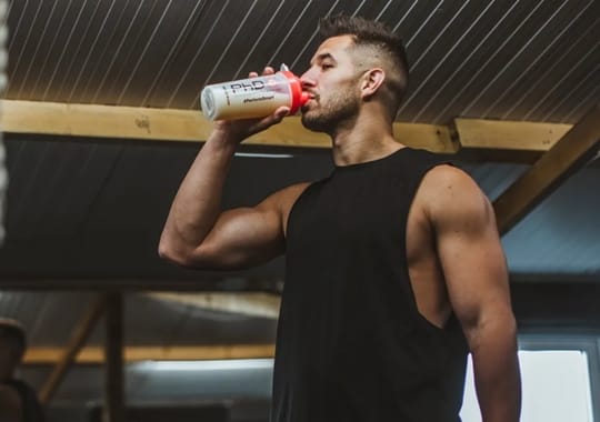 A man holding a bottle drinking protein shake.