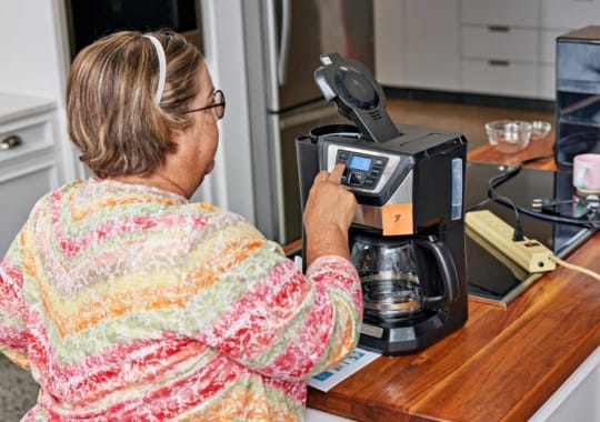 A woman making use of a coffee machine.