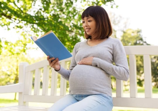 A pregnant woman reading a book.