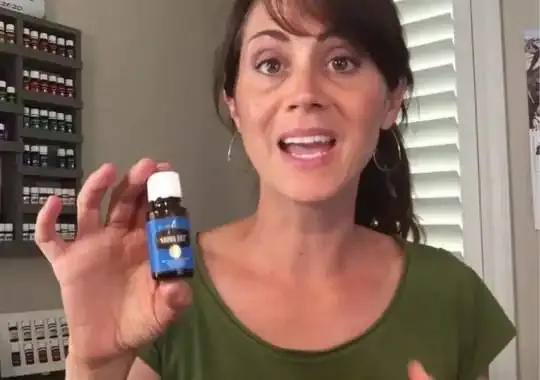 A woman holding a bottle of essential oil.