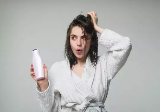 A woman holding a bottle of shampoo.