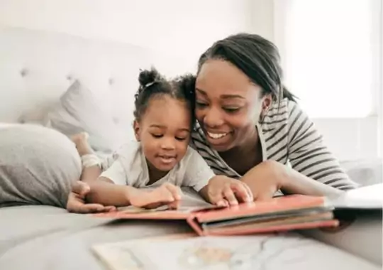 A woman teaching a baby how to read.