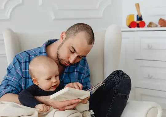 A man reading a book for a baby.