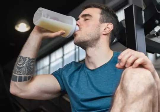 A man drinking protein shake for muscle building.