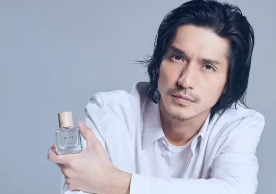 A man holding a bottle of perfume.