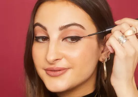 A woman applying eyeliner.