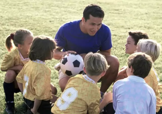A man encouraging children to play sports.
