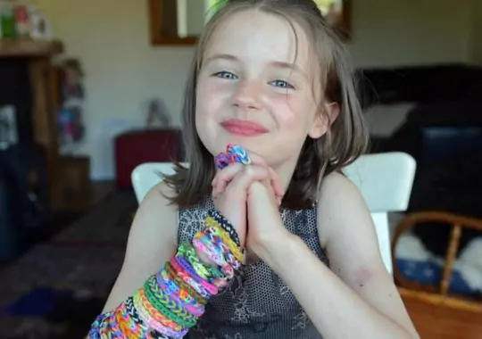 A small girl wearing different types of rubber bands.