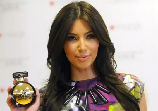 A lady carrying a Kim Kardashian fragrance bottle.