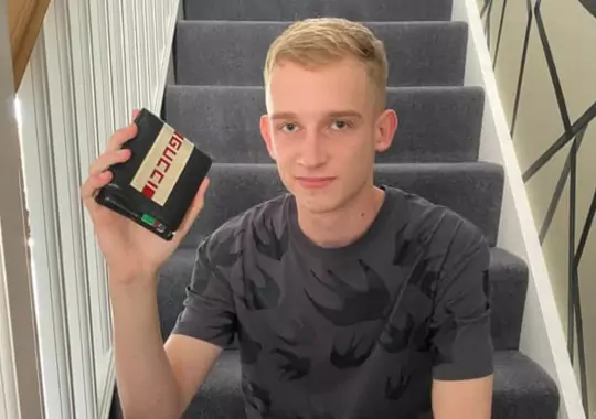 A man holding a gucci wallet.