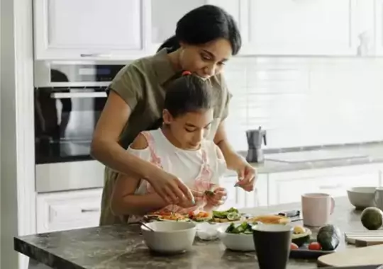 A woman and her child cooking in the kitchen.