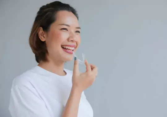 A woman holding an Invisalign.