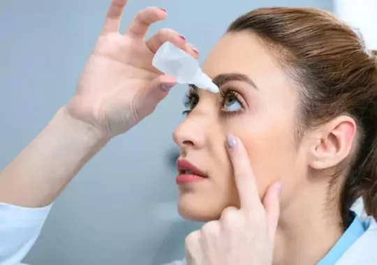 A woman applying eyedrops in the eyes.