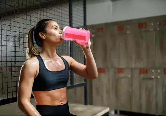 A woman drinking pre-workout supplement.