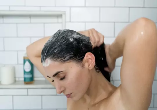 A woman washing her hair with shampoo.
