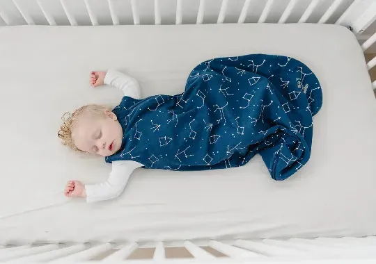 A sleeping baby wearing a Weighted Sleep Sack.