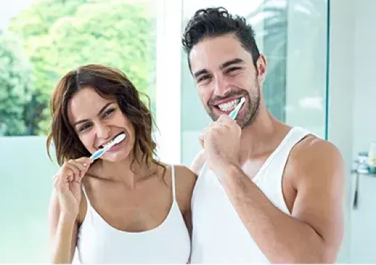 A man and a woman brushing their teeth.