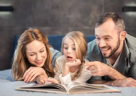 Parents reading with their daughter.