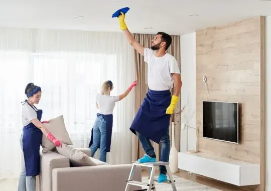 Professional cleaning service team cleans living room in modern apartment.