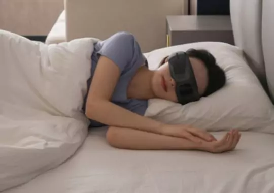 A woman sleeping wearing eye massagers.